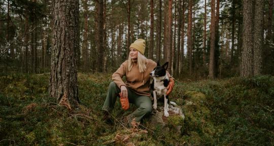Nainen ja koira metsässä