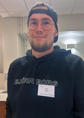 Nuori mies lippalakki väärinpäin päässä katsoo kameraan.