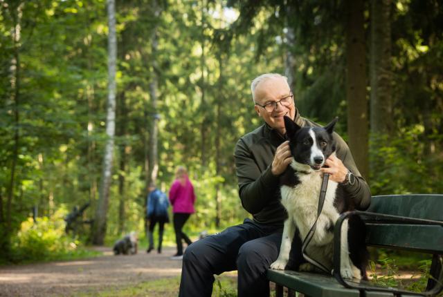 Mies ja koira istumassa penkillä