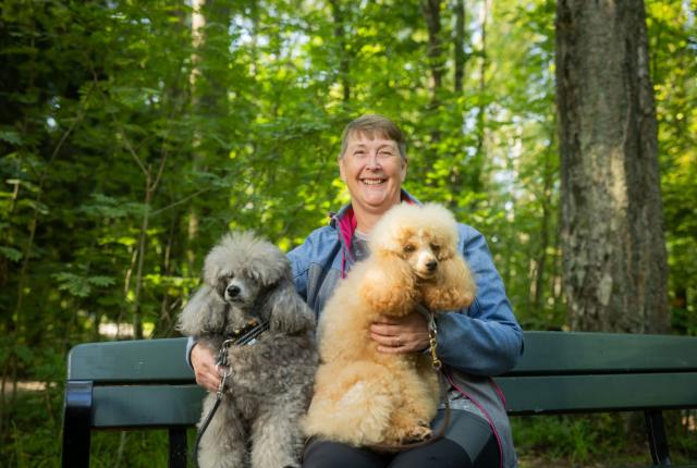 Nainen sylissään kaksi villakoiraa