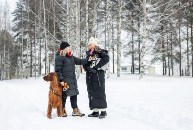 Naiset koirien kanssa ulkona talvisäässä