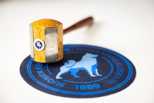 Puheenjohtajan nuija pyöreällä sinisellä alustalla, jossa on Kennelliiton logo