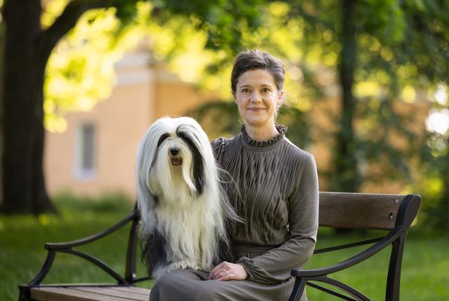 Tanja Hakamo ja tiibetinterrieri istuvat puistossa