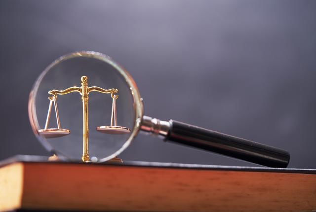 Lakikirja, jonka päällä on suurennuslasi ja vaaka