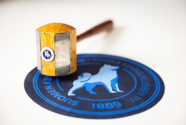 Puheenjohtajan nuija pyöreällä sinisellä alustalla, jossa on Kennelliiton logo