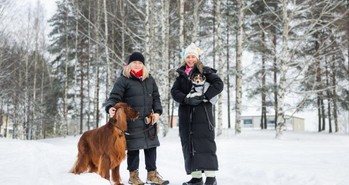 Naiset koirien kanssa ulkona talvisäässä