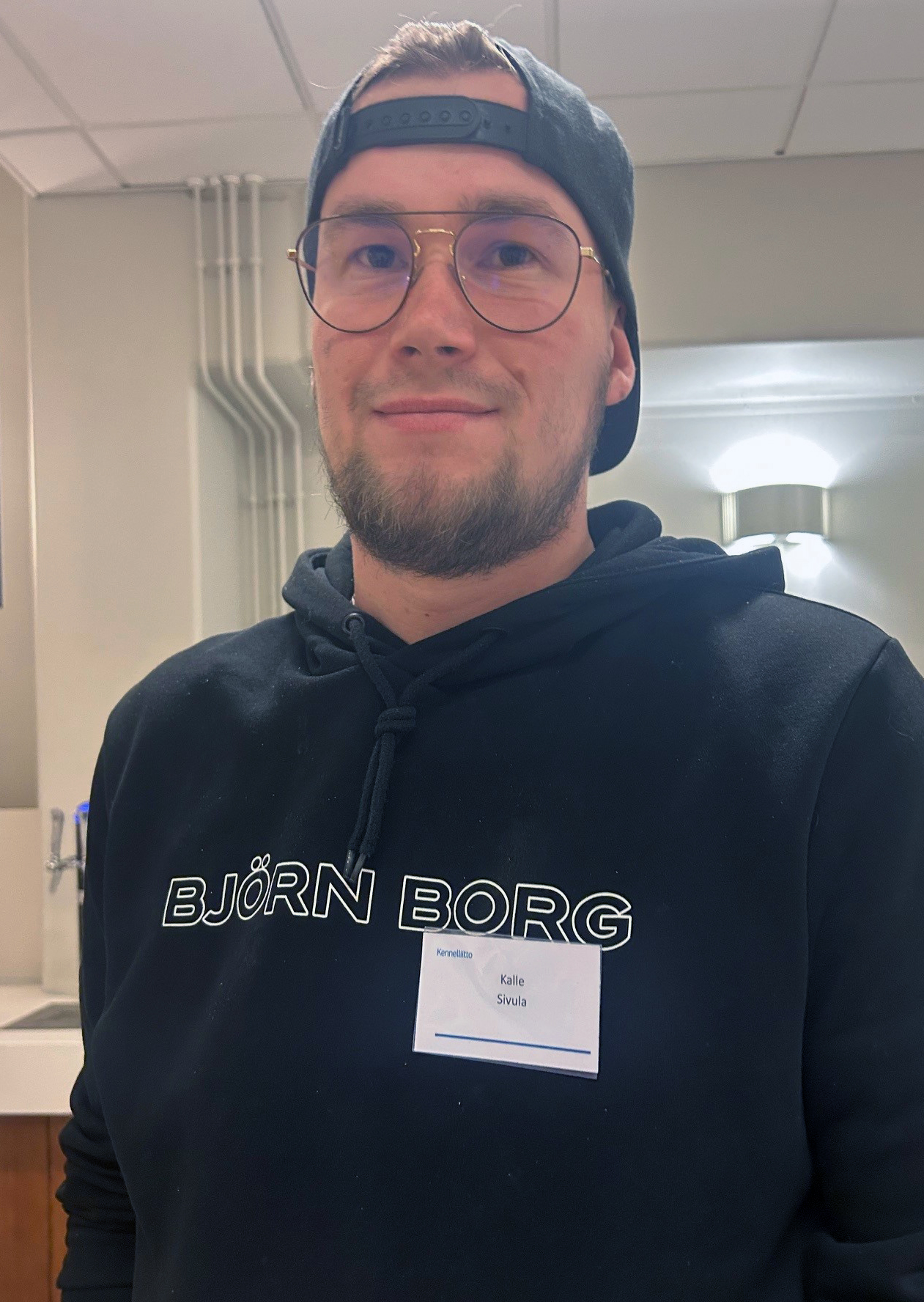 Nuori mies lippalakki väärinpäin päässä katsoo kameraan.