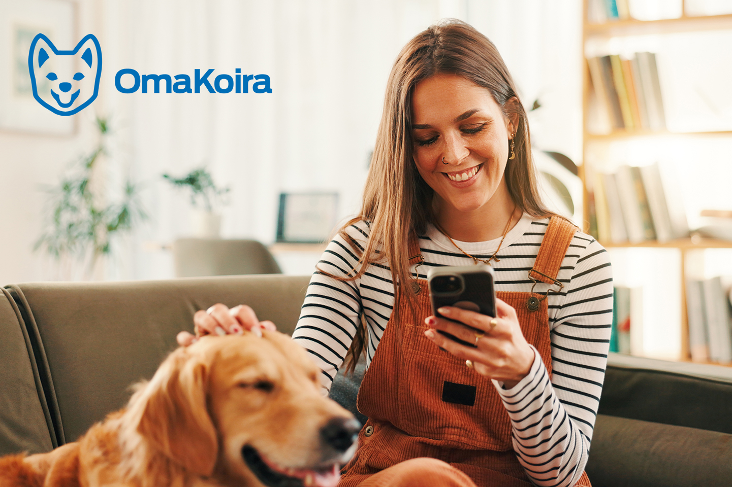 En kvinna sitter i soffan och tittar på mobiltelefonen och klappar en golden retriever