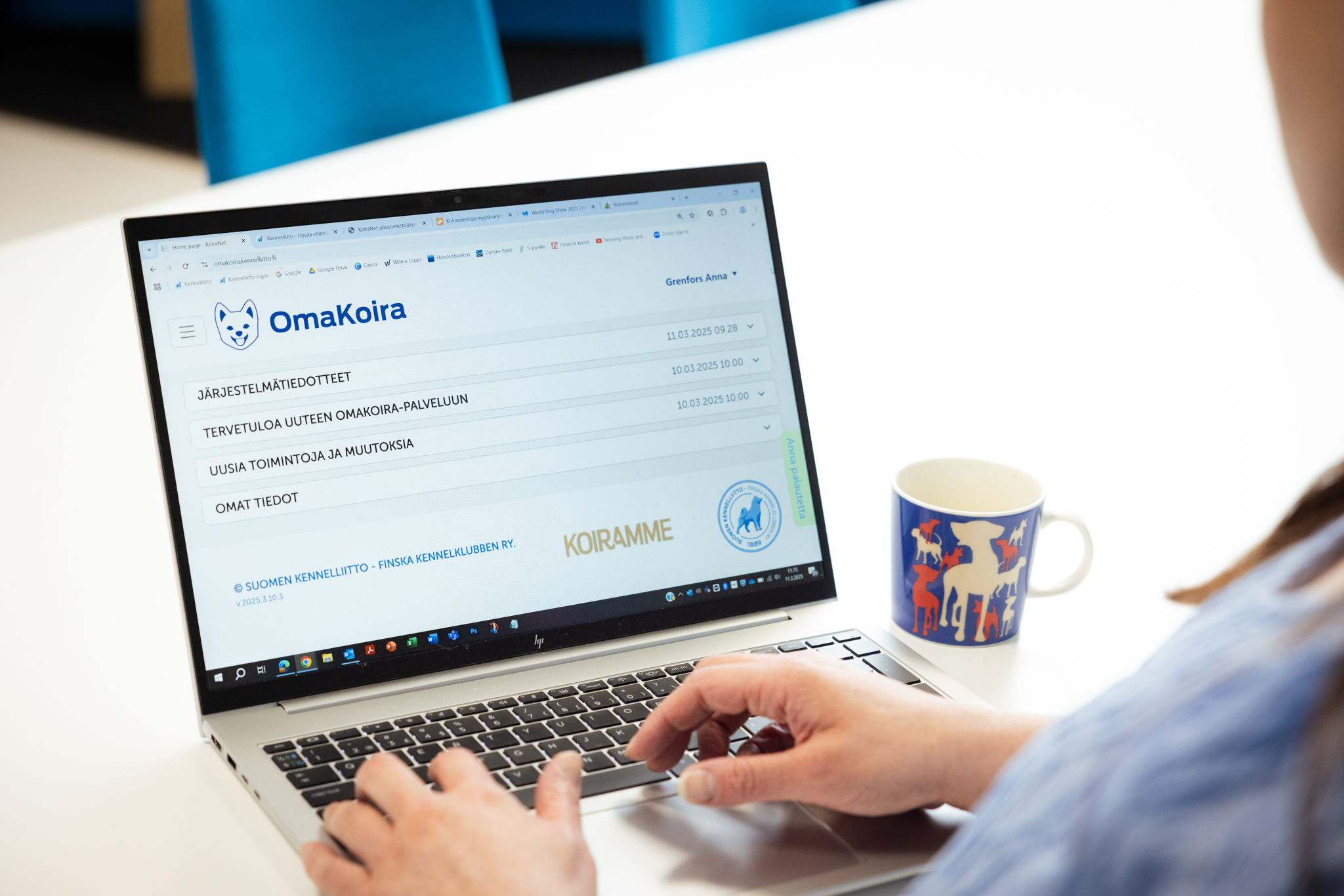 Tietokoneen näytöllä näkyy Omakoira-palvelun aloitussivu, sinipaitainen henkilö istuu koneella ja hänestä näkyy vain osa olkapäästä ja näppäimistöllä olevat kädet